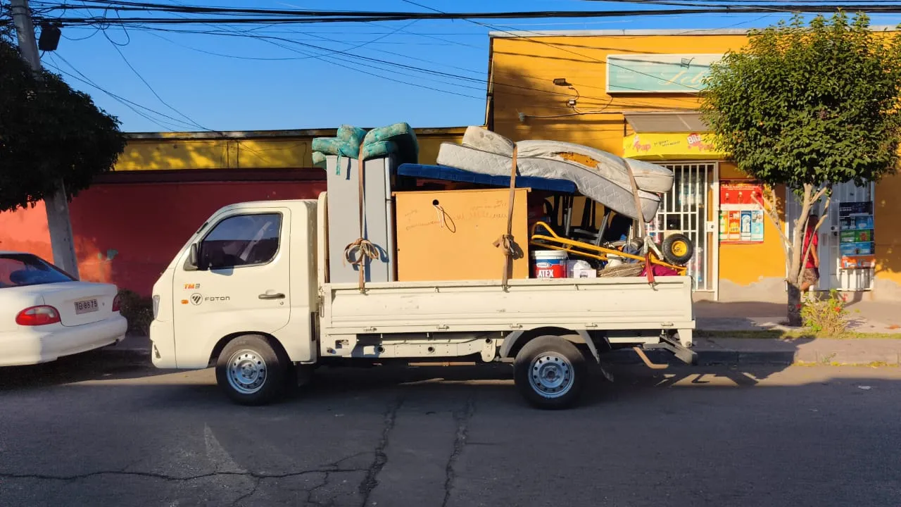 Camión de Fletes Transporte MatCris cargado con muebles, colchones y un refrigerador durante una mudanza en Santiago